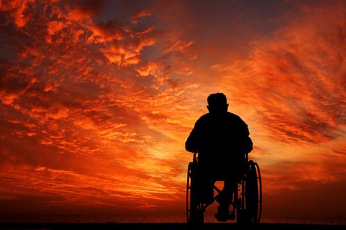 The backdrop is a beautiful sunset Skyline with the silhouette of a person in a wheelchair