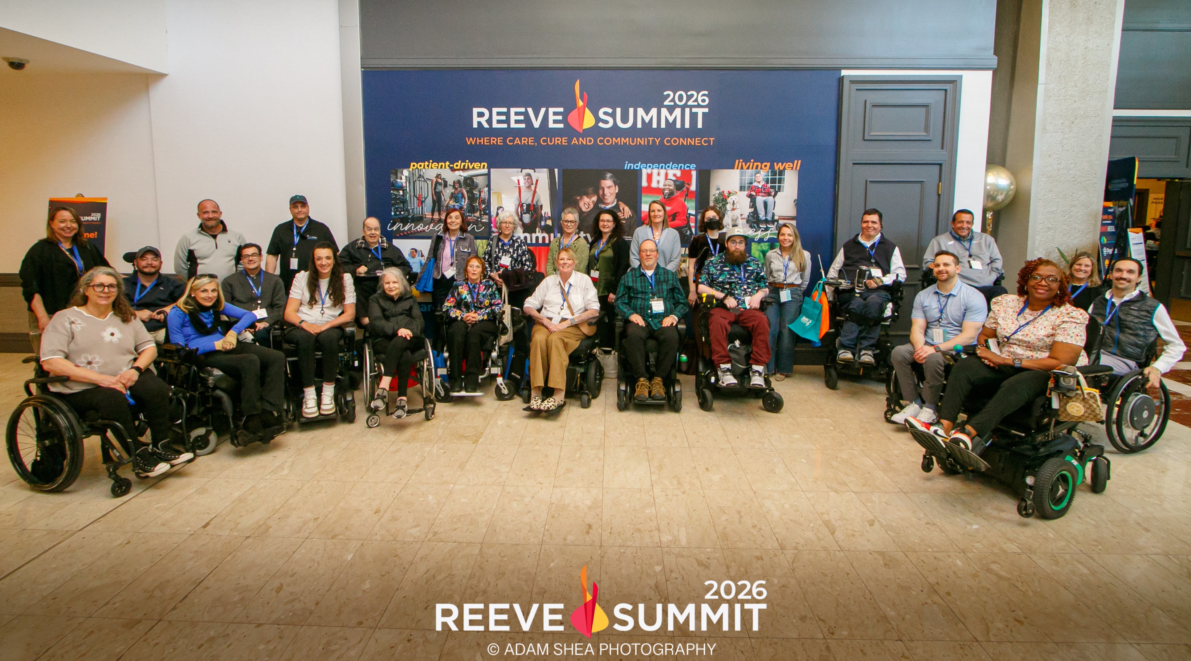 This is an image of all of the SCIboston community attendees at the Reeve Summit 2026 -- plus a few friends. Everyone is in a half circle in front of a Reeve Summit sign